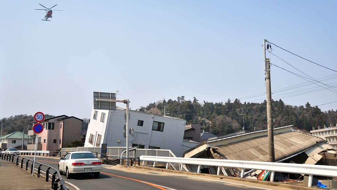 Helicopter over Japanese street with severely damaged buildings by Tohoku megaquake